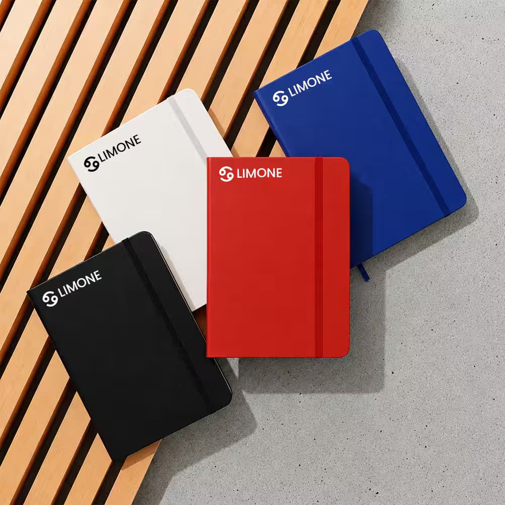 Four personalized diary notebooks in white, blue, black, and red with "LIMONE" logos, arranged on wooden slats and concrete.