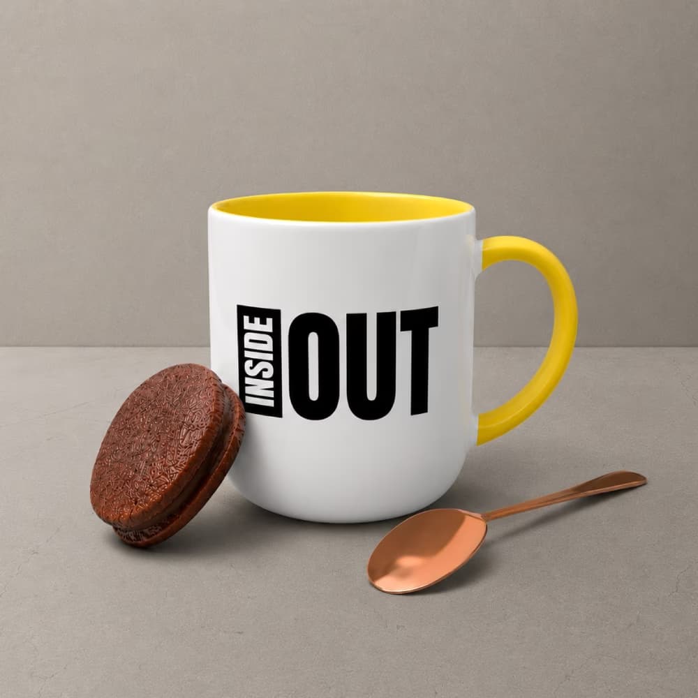A two-tone white and yellow custom bell mug featuring the bold typography "INSIDE OUT" next to a cookie and a copper spoon.